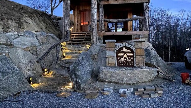 A rustic cabin with a stone entrance, wooden steps, and a green roof. - SKYLINE LODGE~ Spectacular Mountain Escape! (fletcher)