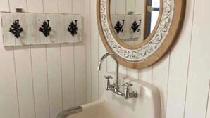 A bathroom with a white sink, a mirror with an ornate frame, and black wall-mounted towel holders. - SKYLINE LODGE~ Spectacular Mountain Escape! (fletcher)