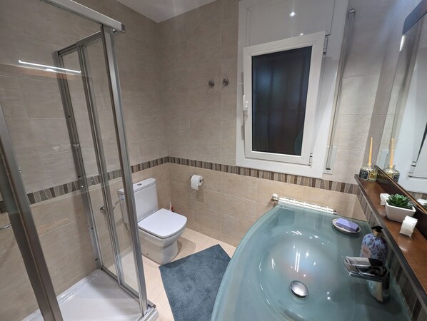 A modern bathroom with a glass shower enclosure, a toilet, a glass sink with a faucet, and a window above the sink. - CASA LOTTCHEN : Villa with private swimming pool, sea view - 3 bedrooms for 6 (Roses)