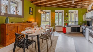 Une cuisine et une salle à manger dotées de poutres en bois, de murs verts et d’appareils électroménagers modernes.