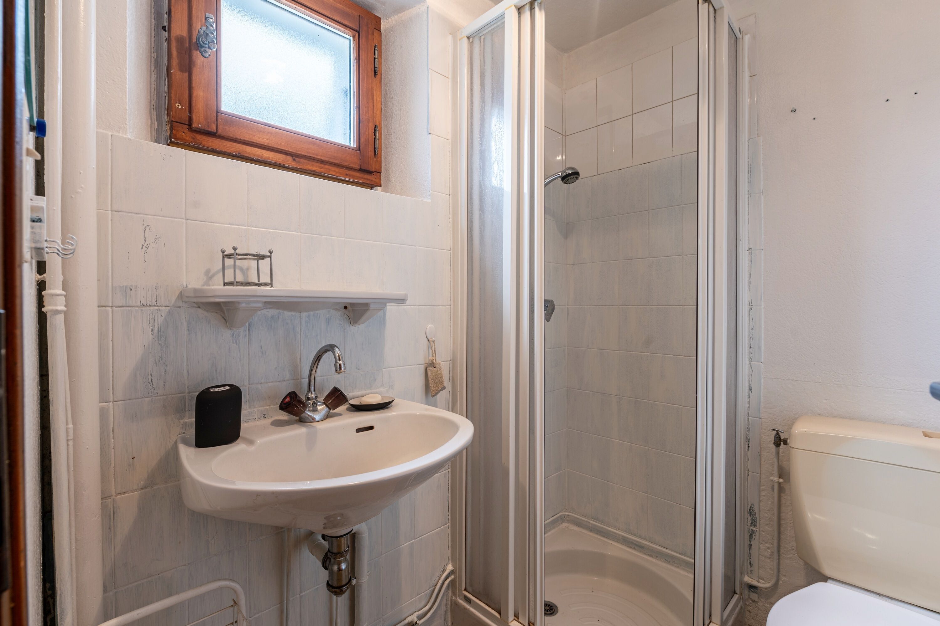 A bathroom with a white sink, a mirror above it, and a shower area.