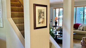 A spacious living area with a staircase leading to another level, a framed picture on the wall, and a cozy seating area with a couch and a patterned chair. - Charming light-filled 5-bedroom home (Wilmette)