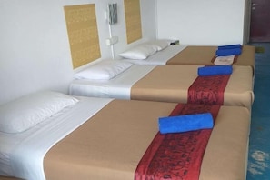 Une chambre d’hôtel avec deux lits, chacun doté d’un oreiller blanc et d’une couverture de lit beige.