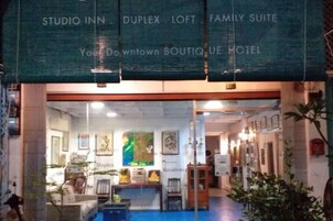 La entrada de un hotel boutique con fachada de vidrio, obras de arte enmarcadas y suelo cubierto de alfombra azul.