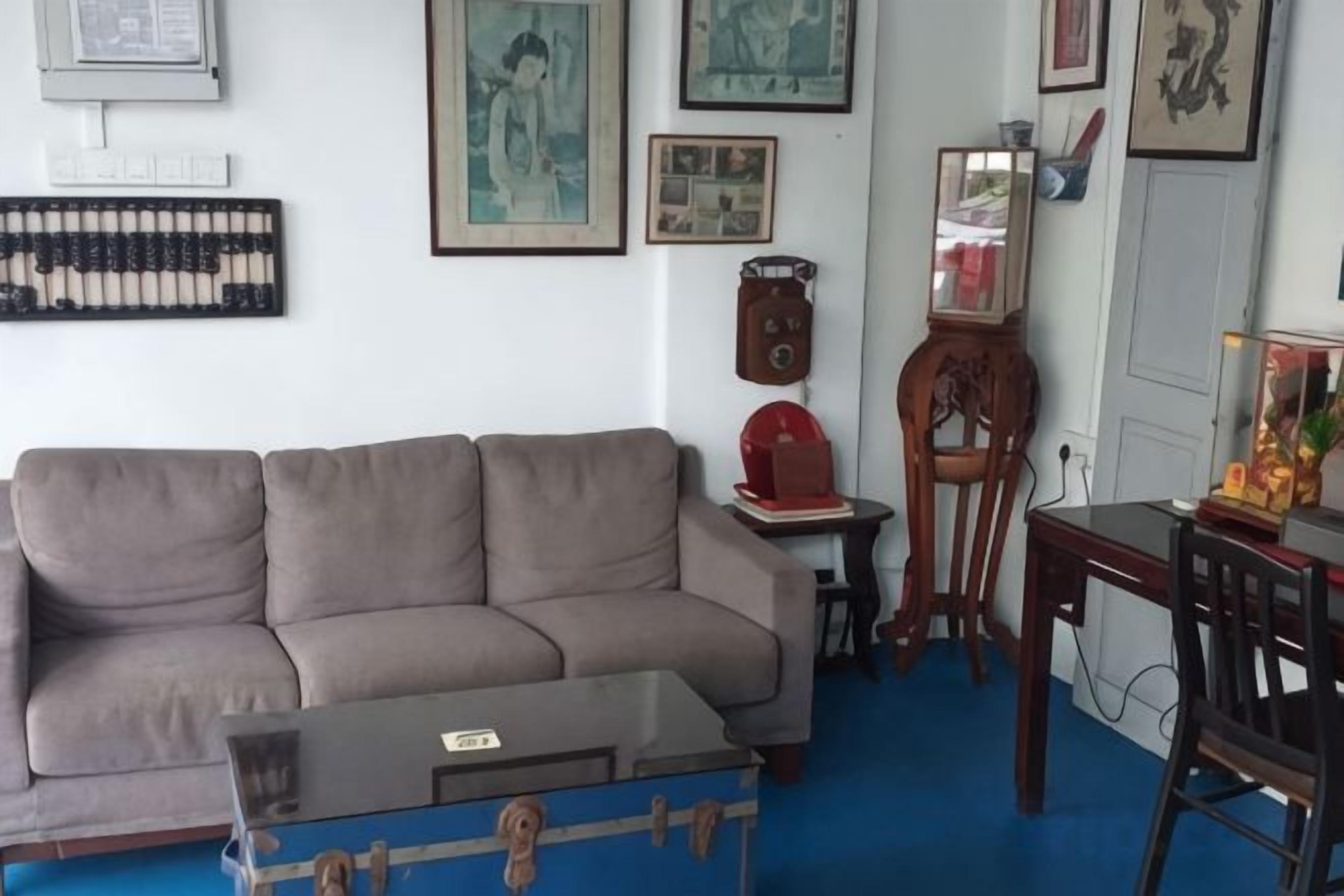Un salon comprenant un canapé, une table basse, une chaise en bois et une petite table sur laquelle se trouve une horloge.