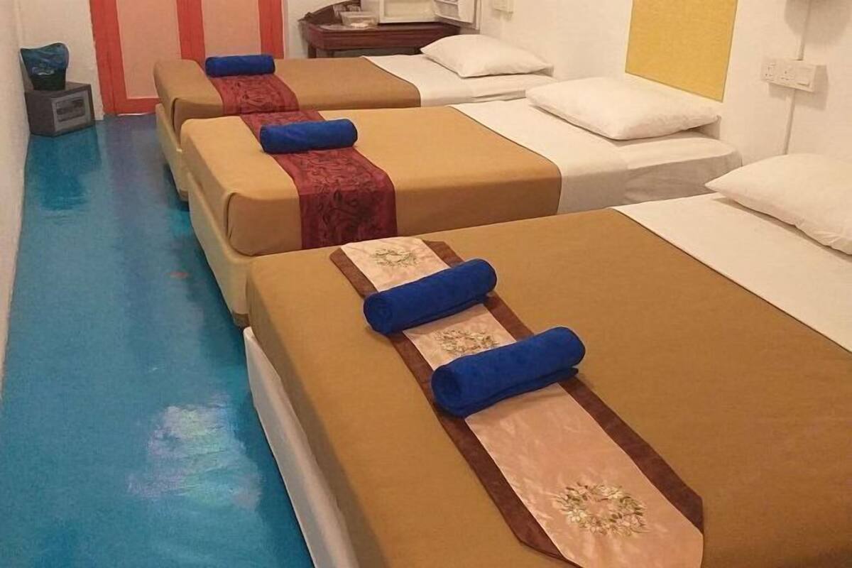 A hotel room with two beds, each with a blue headboard and a decorative pillow.