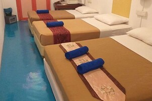 Una habitación de hotel con dos camas, cada una con cabecera azul y un cojín decorativo.