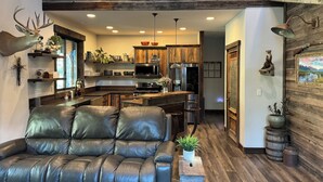 A modern kitchen with wooden cabinets, a black leather sofa, and a rustic decor theme.