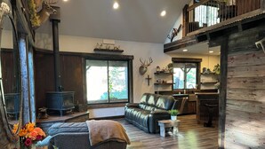 A cozy living room with a fireplace, a sofa, a dining area, and a kitchen.