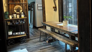 A rustic interior with a wooden table, bench, and a coffee cart.