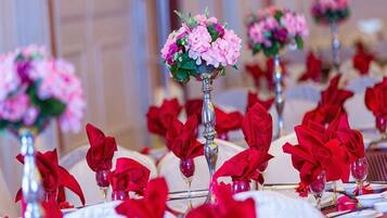 A table set with red napkins and a centerpiece with pink flowers.
