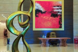 Un vestíbulo con una escultura moderna, un cuadro abstracto grande y un mostrador de recepción.