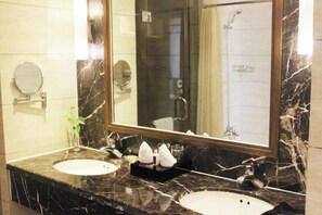 Un baño con dos lavamanos, un espejo grande y una ducha.