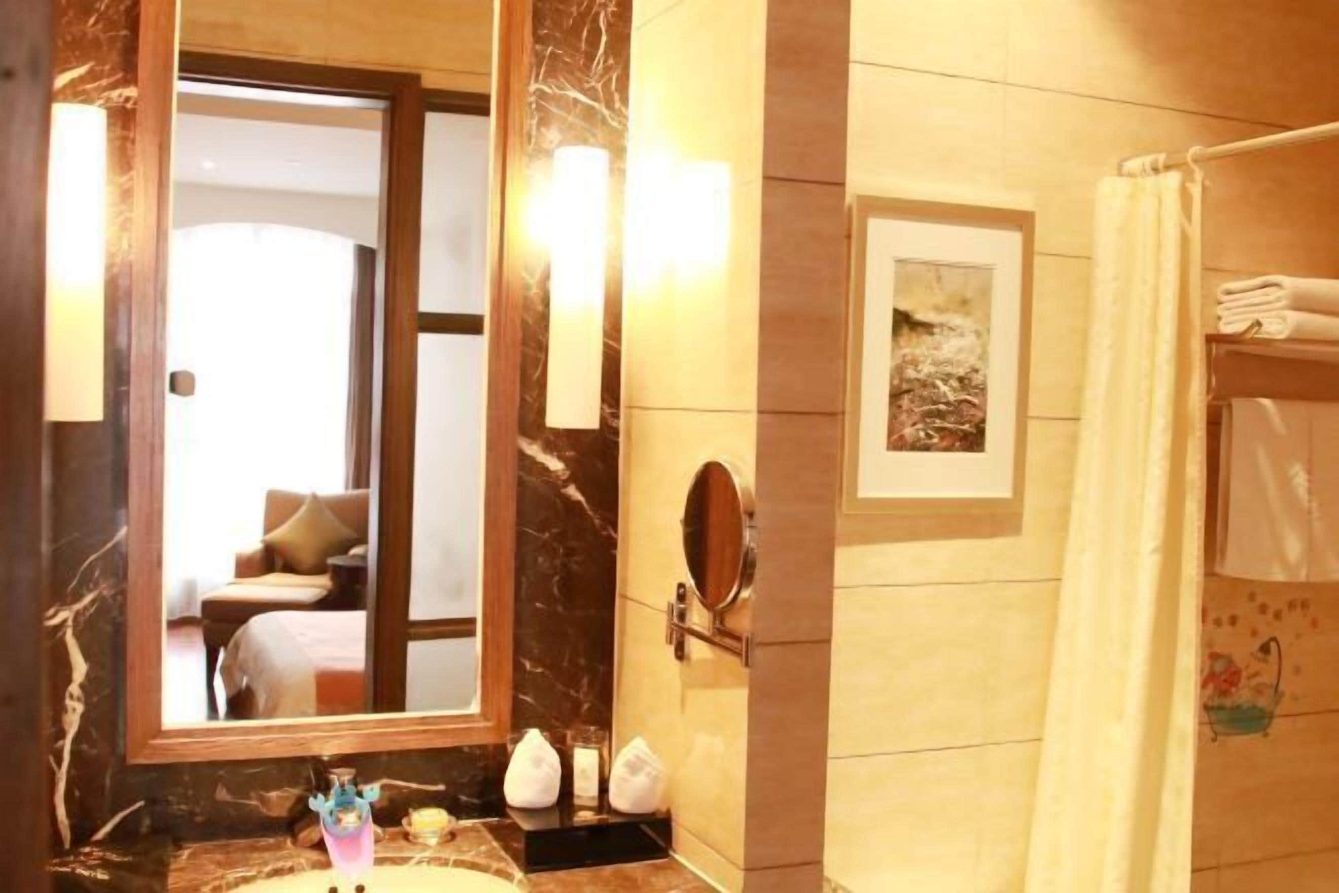 A bathroom with a marble countertop, a sink, a mirror, a framed picture on the wall, and a shower curtain.