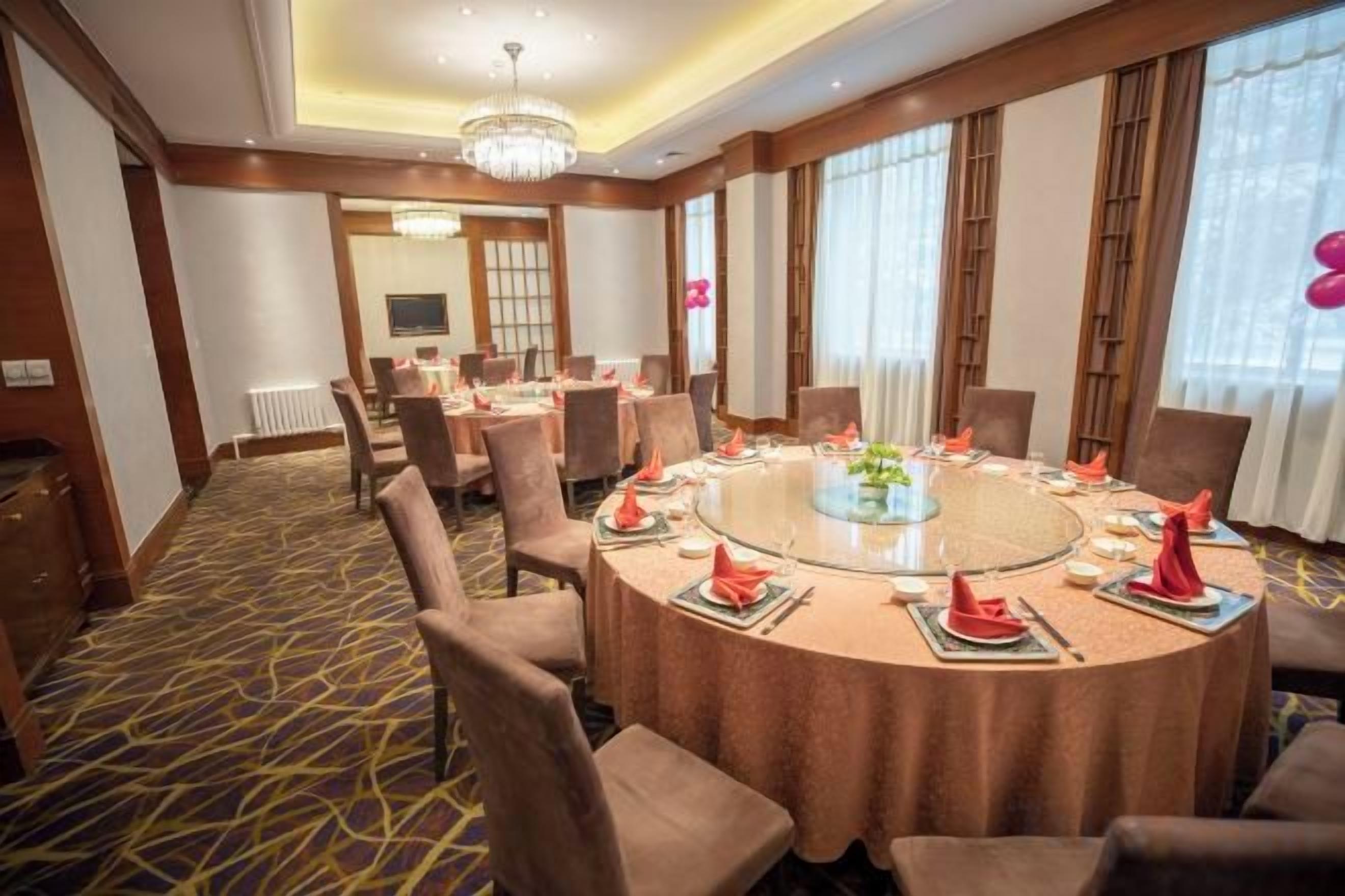 Une salle de conférence avec une table ronde, des chaises et un lustre.