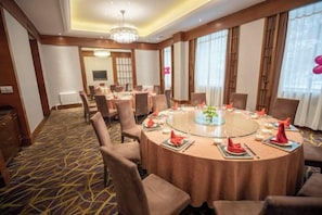 Uma sala de conferências com uma mesa redonda, cadeiras e um lustre.