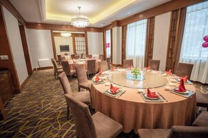 Un salón de conferencias con una mesa redonda, sillas y una araña.