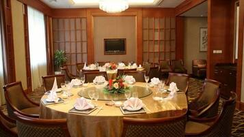A conference room with a round table, multiple chairs, and a chandelier.