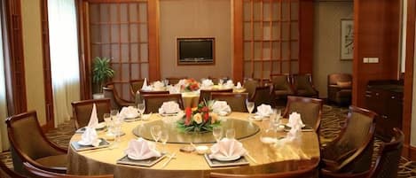 A conference room with a round table, multiple chairs, and a chandelier.