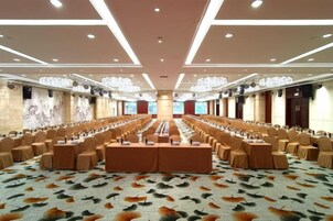 Un salón de conferencias con una larga mesa, varias sillas y una alfombra con motivos de hojas.