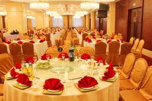 Un salón de banquetes con mesas redondas dispuestas para un evento formal, con un pasillo central y filas de sillas.