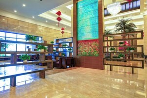 A spacious lobby with a reception desk, seating area, and decorative plants.