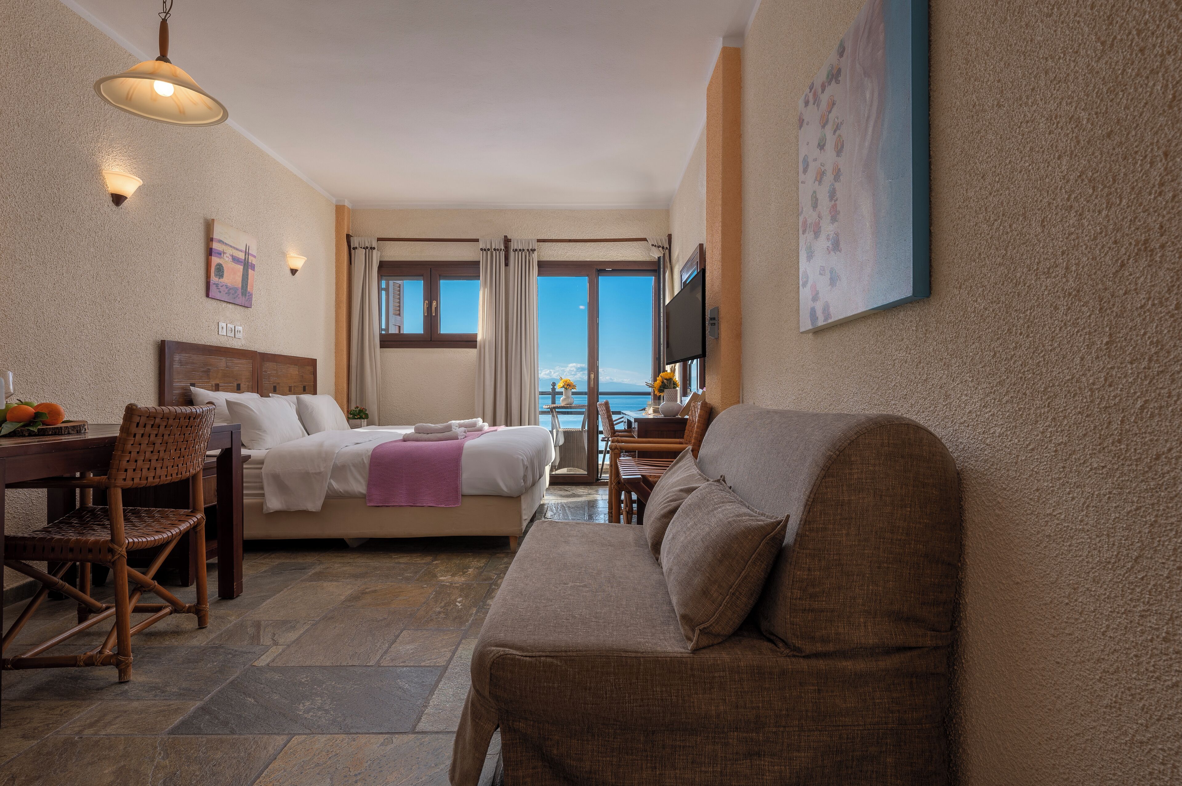 Une chambre d’hôtel avec un lit, un canapé, une table à manger et un téléviseur.