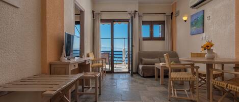 A room with a balcony, a TV, a dining table, and a sofa.