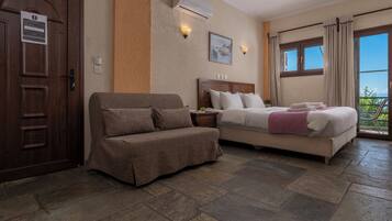 Una habitación de hotel con una cama, un sofá, una puerta de madera y una ventana con cortinas.
