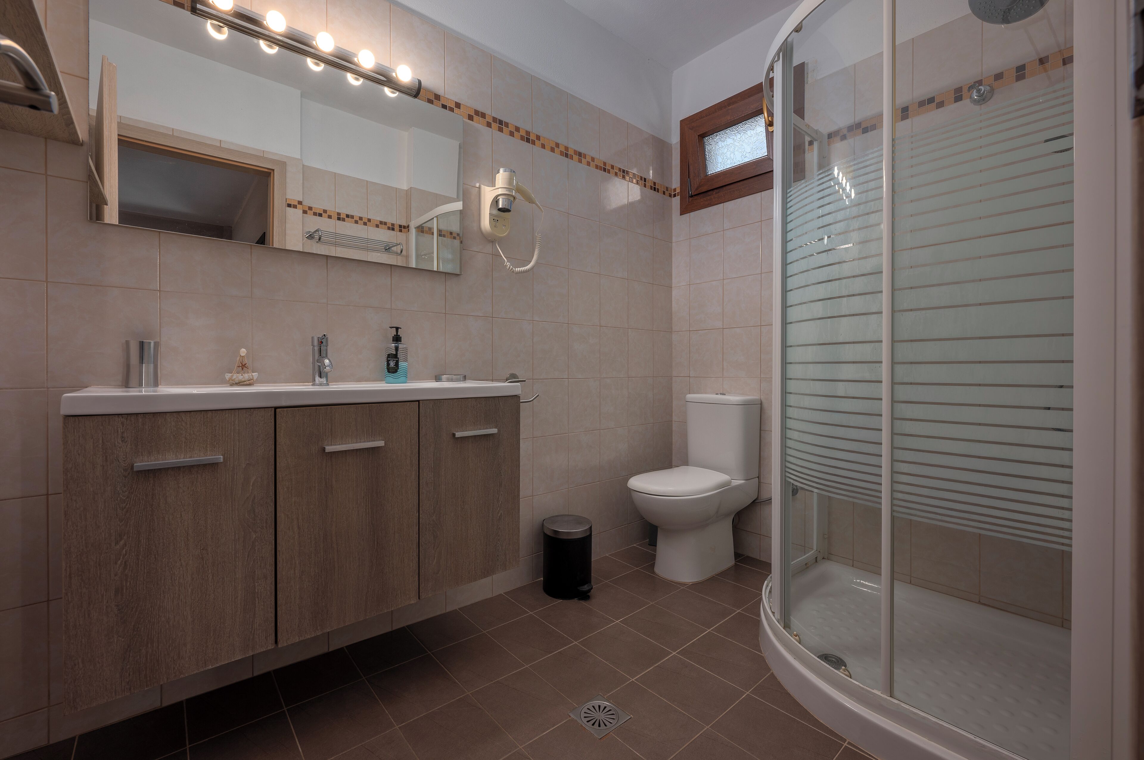 Une salle de bain équipée d’un meuble-lavabo, de toilettes et d’une douche à parois de verre.