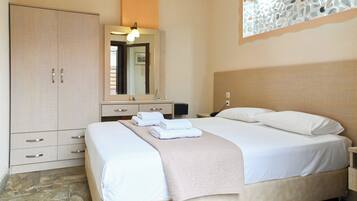 A neatly arranged bedroom with a bed, a wardrobe, a nightstand, and a mirror.