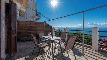 Une terrasse avec une table et des chaises, offrant une vue panoramique sur la mer et les montagnes.