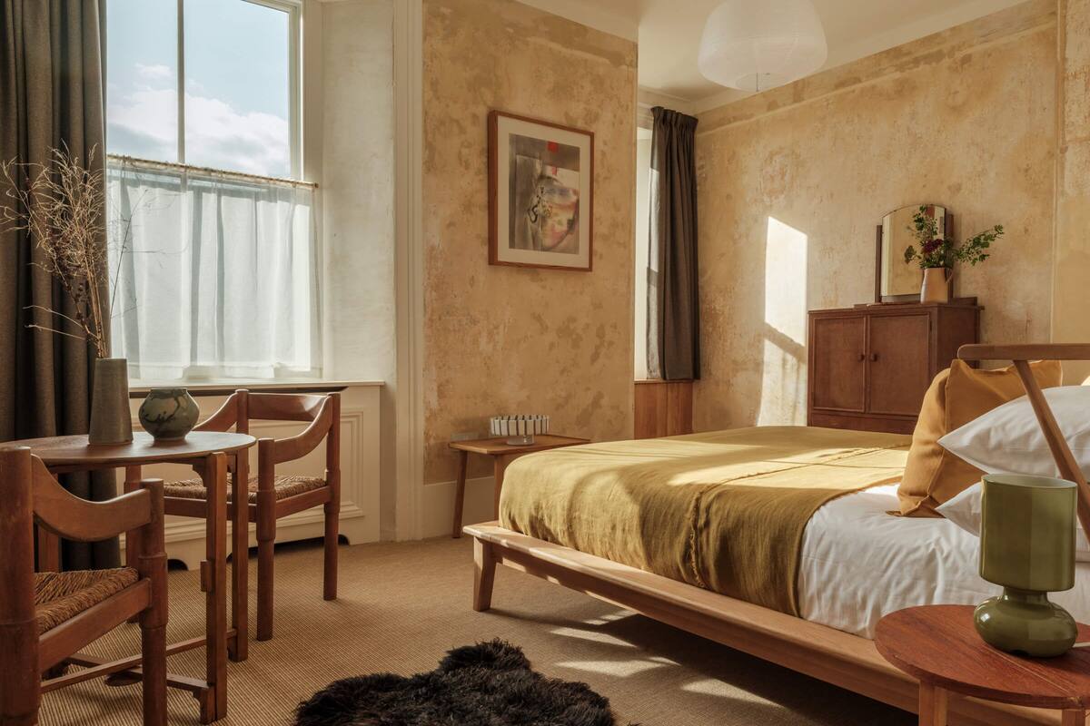 A cozy bedroom with a wooden bed, a small table, and a chair.