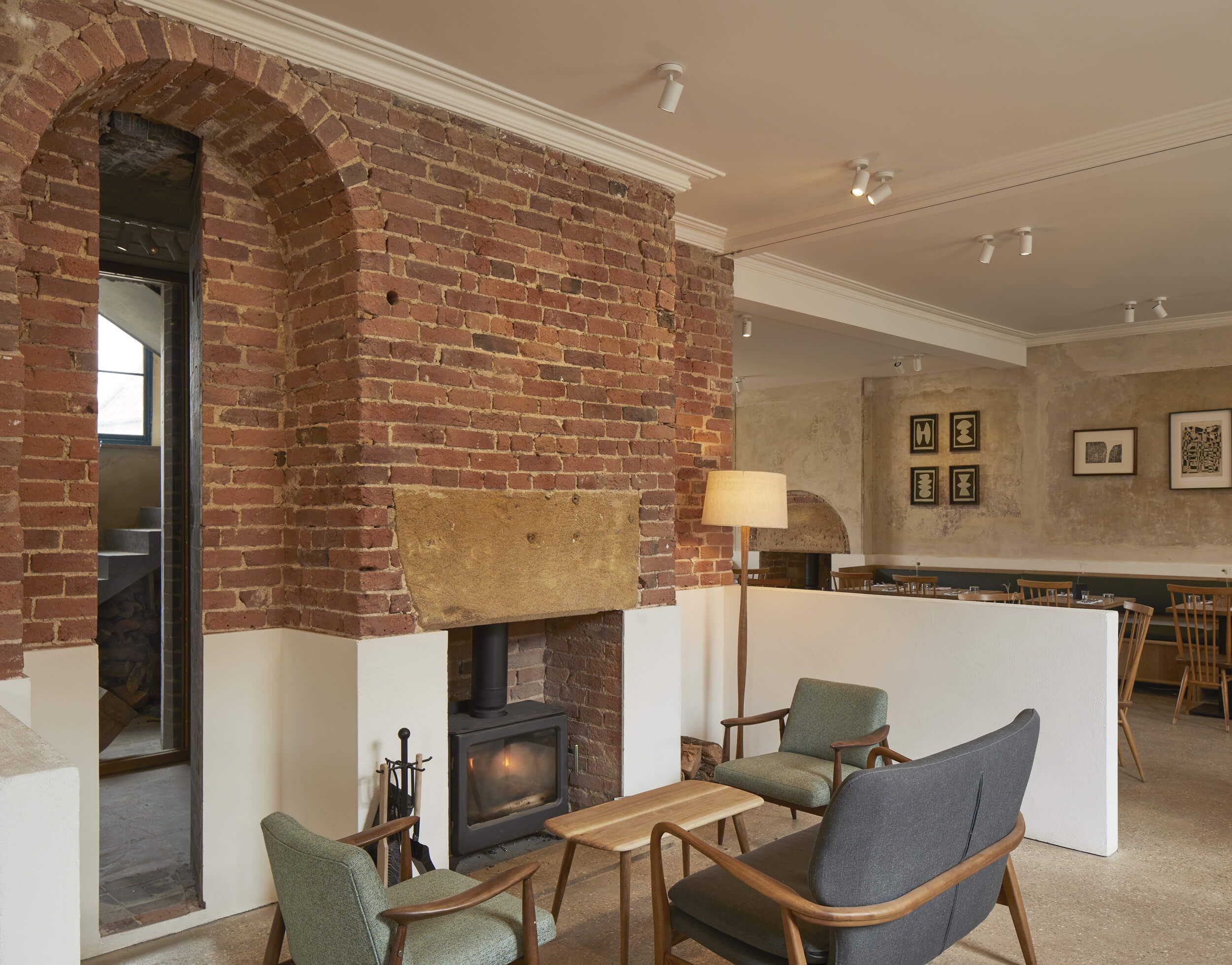 A cozy living room with a brick fireplace, comfortable seating, and a dining area.