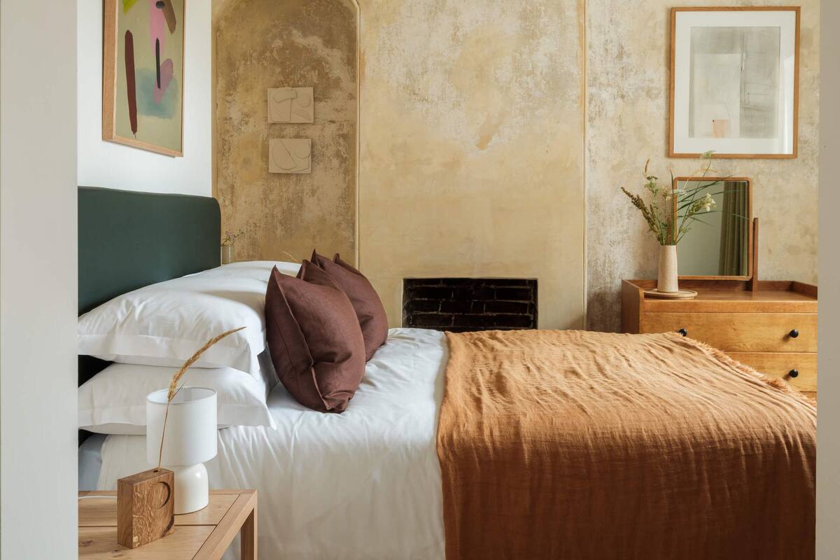 A bedroom with a bed, a dresser, a mirror, and a fireplace.