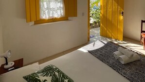 Un dormitorio con una cama, un ventanal con cortinas, un ventilador de techo y una puerta que da al exterior.