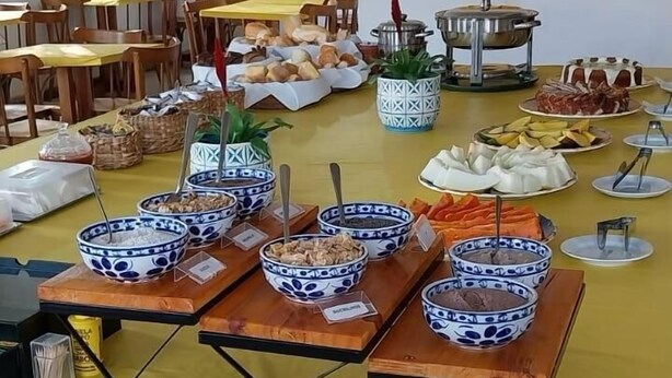 Un comedor con varias mesas, sillas y una barra de buffet con distintos alimentos y recipientes.