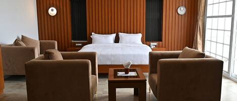 A hotel room with a large bed, two side tables, a coffee table, and two sofas.