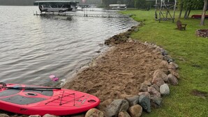 A lakeside area with a kayak, a boat dock, and a grassy bank. - Charming Family Cabin in Crosslake (Crosslake)
