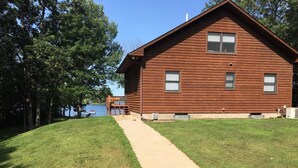 A wooden cabin with a concrete pathway leading to a dock. - Charming Family Cabin in Crosslake (Crosslake)