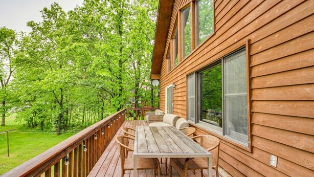 A wooden deck with outdoor seating and a view of a forest. - Charming Family Cabin in Crosslake (Crosslake)