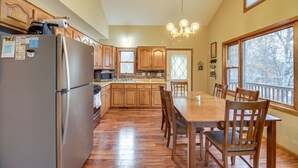 A kitchen with wooden cabinets, a stainless steel refrigerator, a dining table with chairs, and a chandelier. - Charming Family Cabin in Crosslake (Crosslake)