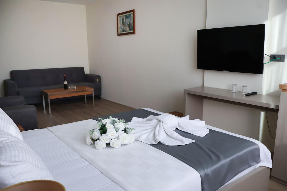 A hotel room with a bed, a sofa, a coffee table, a TV, and a desk.