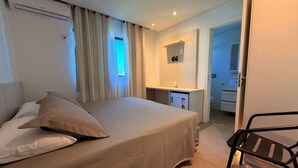 A hotel room with a bed, a desk, a chair, and a small kitchenette. - Hotel Mais Lazer (Joinville)