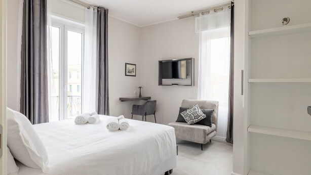 A hotel room with a bed, a desk, a chair, a TV, and a wardrobe. - Belli San Giovanni Guest House (Rome)