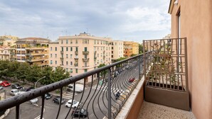 A balcony with a view of a busy street and surrounding buildings. - Belli San Giovanni Guest House (Rome)
