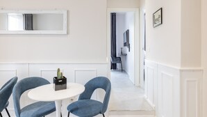 A modern room with a white round table, two blue chairs, a mirror, and a cactus on the table. - Belli San Giovanni Guest House (Rome)