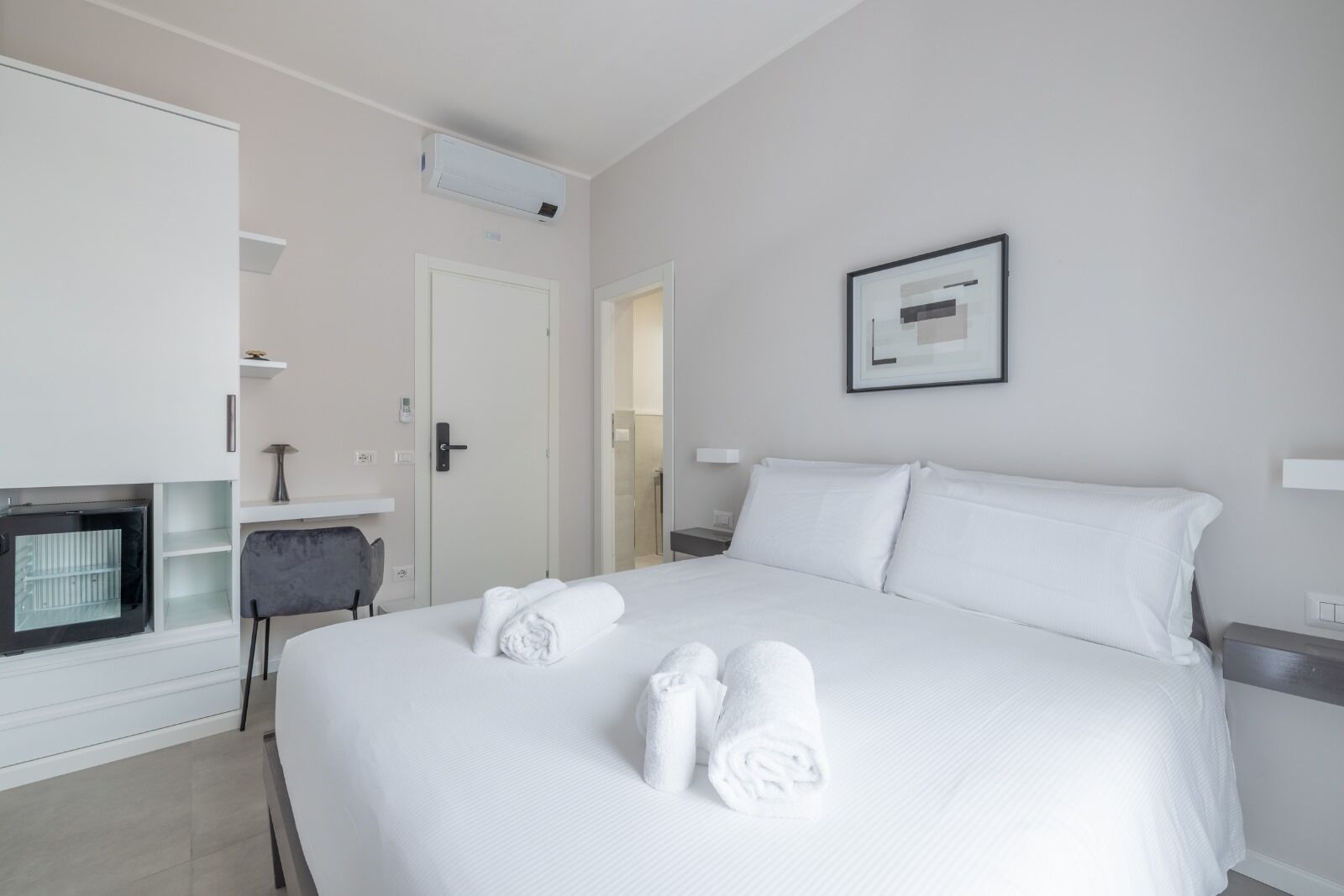 Ein Hotelzimmer mit einem großen Bett, einem Schreibtisch, einem Sessel, einem Fernseher und einem gerahmten Bild an der Wand.