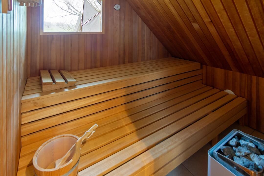 Eine Holzsauna mit Bänken und einem Eimer Steine.