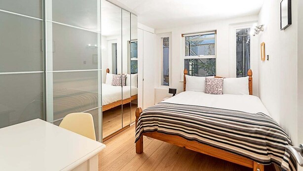 A bedroom with a bed, a desk, and a chair. There are two windows and a door with a mirror. - Richmond Hill Top Apartment (London)